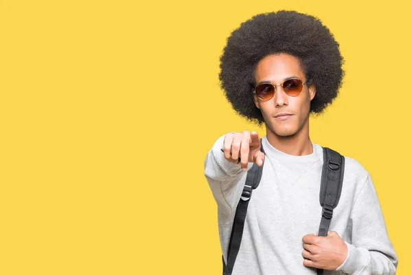 非洲青年美国男子戴着太阳镜 背包用手指指着镜头 对着你 手的牌子 积极和自信的手势从前面 — 图库照片