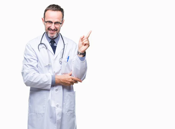 中年の白髪の先輩医師の男性の顔に大きな笑みを浮かべて医療制服孤立した背景を着てカメラを見て側の手と指で指す — ストック写真