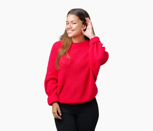 噂やゴシップに審理をリスニングの耳に手を浮かべて隔離された背景に赤冬のセーターを着た若い美しいブルネット女性 難聴の概念 — ストック写真