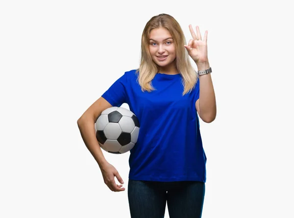 優秀なシンボルの指で サインをして孤立した背景にサッカー ボールを保持している若い白人女性 — ストック写真