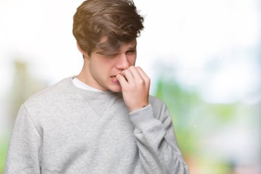 Genç yakışıklı sportif adam stresli ve gergin ile izole arka plan üzerinde sweatshirt giyen tırnak ısırma dudaklarından eller. Anksiyete sorunu.