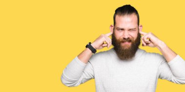 Yüksek sesle müzik gürültü rahatsız ifade parmaklarıyla kulaklarıyla kapsayan geçici kazak giyen genç sarışın adam. Sağır kavramı.