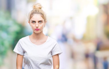 Yüzünde ciddi bir ifade ile izole arka plan üzerinde beyaz t-shirt giyen genç güzel sarışın bir kadın. Basit ve doğal kameraya bakıyor.