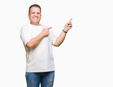 Orta yaş Arap adam wearig gülümseyerek ve iki elleri ve parmakları ile tarafına işaret kamera bakarak arka plan beyaz t-shirt üzerine izole.
