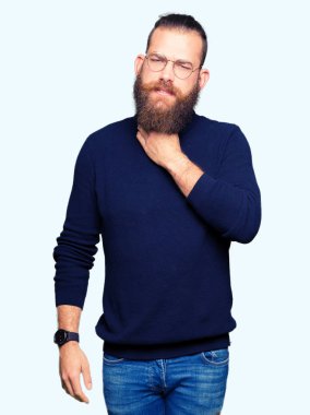 Gözlük ve balıkçı yaka kazak giyen genç sarışın adam ağrılı boyun, boğaz gribi, kesek ve enfeksiyon için dokunaklı