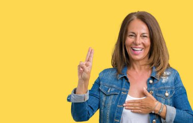 Casual denim ceket izole üzerinde giyen güzel orta yaş kadın arka plan Swearing göğüs ve parmaklar, el ile bir sadakat sözü yemin yapma