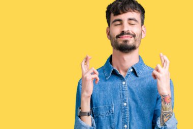 Yakışıklı delikanlı geçiş parmakları umut ve gözleri kapalı ile gülümseyen izole arka plan üzerinde. Şans ve batıl kavramı.