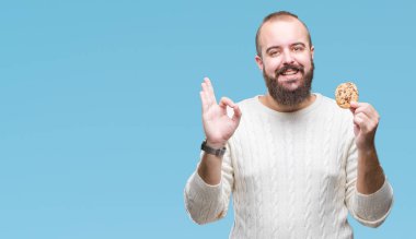 Genç hipster man parmak, mükemmel sembolü ile ok işareti yapıyor izole arka plan üzerinde çikolata çerez yemek