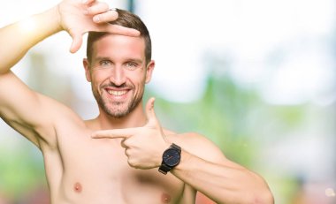 Gömleksiz yakışıklı gösteren çıplak göğüs elle yapma çerçeve ve parmakları ile mutlu yüz gülümseyerek. Yaratıcılık ve Fotoğrafçılık kavramı.