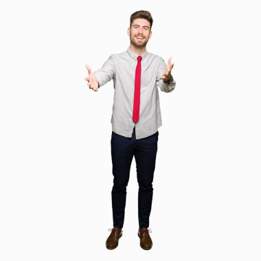 Genç yakışıklı iş adamı sarılmak için kollarını açarak gülümseyen kamera bakıyor. Neşeli ifade kucaklayan mutluluk.