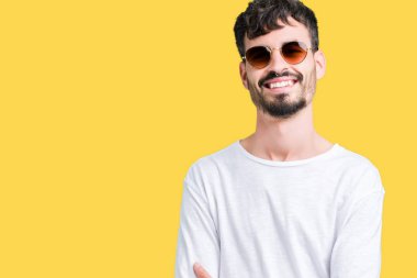 Yakışıklı delikanlı üzerinde güneş gözlüğü takıyor mutlu yüz ile gülümseyerek kameraya seyir silah geçti arka plan izole. Olumlu bir kişi.