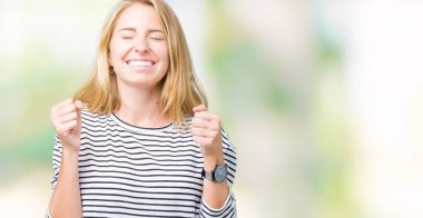 Zafer kutluyor gülümseyen izole arka kolları olan başarı için heyecan üzerinde çizgili süveter giyen güzel genç kadın kaldırdı. Kazanan kavramı.