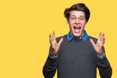 Genç yakışıklı zarif adam deli kutluyor ve silah ile başarı için heyecanlı çığlık kaldırdı ve açık gözleri hayret izole arka plan üzerinde. Kazanan kavramı