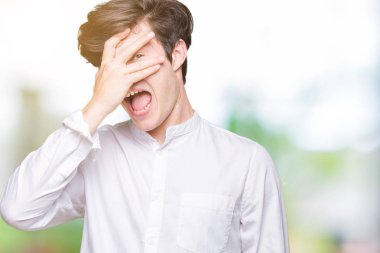 Mahcup ifadeyle parmaklarımın arasından seyir yüz ve gözler el ile kapsayan şok izole arka plan bakmak üzerinde genç yakışıklı iş adamı.