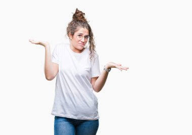 Güzel genç esmer kıvırcık saçlı kız gözlüklü üzerinde arka plan clueless ve şaşkın bir ifadeyle kollar ve eller kaldırdı izole. Şüphe kavramı.