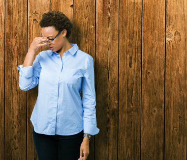 Genç güzel Afro-Amerikan iş kadını izole arka plan yorgun sürtünme burun ve göz yorgunluğu ve baş ağrısı hissediyor. Stres ve hayal kırıklığı kavramı.