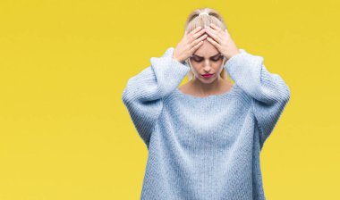 Çünkü çaresiz ve stresli baş ağrısı acı izole arka plan üzerinde kış kazak giyen genç güzel sarışın ve mavi gözlü kadın ağrı ve migren. Ellerini kafasına.