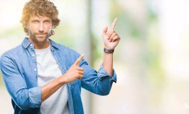 Yakışıklı İspanyol modeli erkek gülümseyen ve iki elleri ve parmakları ile tarafına işaret kamera bakarak izole arka plan üzerinde.