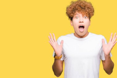 Çılgın ve silah ile başarı için hayran kutluyor casual beyaz t-shirt giyen afro saçlı yakışıklı delikanlı kaldırdı ve açık gözleri çığlık heyecanlı. Kazanan kavramı