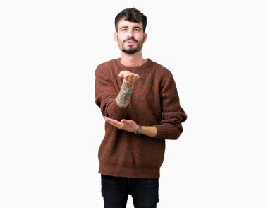 Bir öpücük el ile güzel ve seksi olmak hava üfleme kamera bakarak izole arka plan üzerinde kış kazak giyen genç yakışıklı adam. Aşk ifade.