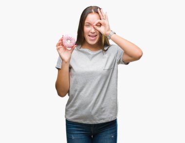 Mutlu yüz el parmaklarının arasından seyir göz üzerinde ok işaretiyle yapıyor gülümseyen izole arka plan üzerinde tatlı çörek yeme genç kafkas kadın