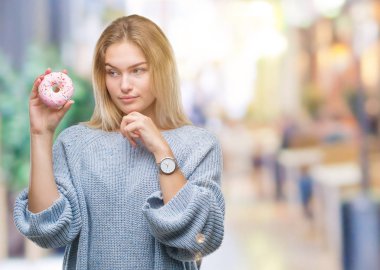 İzole arka plan ciddi bir yüz düşünme hakkında soru, çok karışık bir fikir üzerinde tatlı çörek yiyen genç kafkas kadın