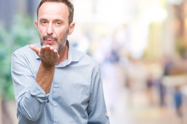 Orta yaş ağarmış üst düzey iş adamı bir öpücük el ile güzel ve seksi olmak hava üfleme kamera bakarak izole arka plan üzerinde. Aşk ifade.