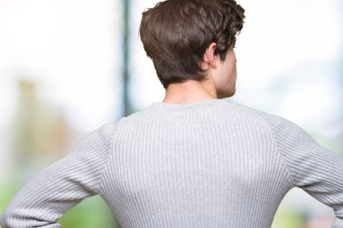 İzole arka plan ayakta geriye doğru uzakta silah ile vücut üzerinde seyir üzerinde kış kazak giyen genç yakışıklı adam