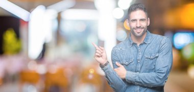 Kameraya bakarak yan el ve parmak ile işaret eden genç yakışıklı adam yüzünde kocaman bir gülümseme ile izole arka plan üzerinde.