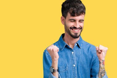 Soyutlanmış, mutlu ve heyecanlı genç bir adam kollarını kaldırmış, gülümseyen ve başarı için çığlık atan kazanan bir jest yapıyor. Kutlama konsepti.