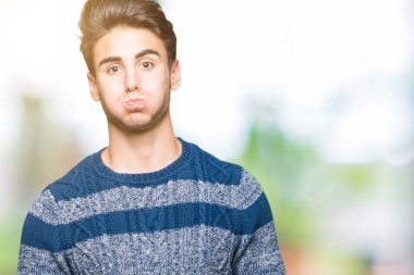 Komik surat ile yanakları şişirme izole arka plan üzerinde genç yakışıklı adam. Ağız ile hava, deli ifade şişirilmiş.