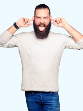 Casual kazak gülen çekerek kulakları parmaklar, komik jest ile giyen genç sarışın adam. Seçmelere sorun