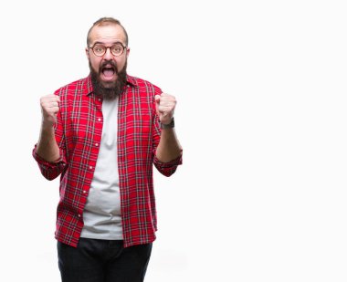 İzole arka plan üzerinde kutluyor gözlük takan Genç beyaz hipster adam şaşırttı ve başarı için kaldırdı kollarını açarak hayret ve gözleri açık. Kazanan kavramı.
