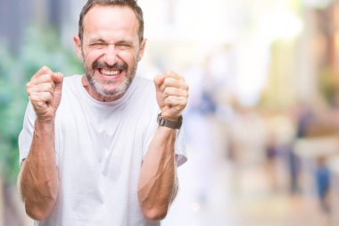 Orta yaş ağarmış komuta sizde izole arka kolları olan başarı için heyecan üzerinde beyaz t-shirt giyen zafer kutluyor gülümseyen kaldırdı. Kazanan kavramı.