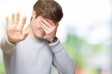 Yakışıklı delikanlı üzerinde kış kazak giyen izole elleriyle gözlerini kapsayan arka plan ve stop jest ile acı ve korku ifadesi. Utandım ve negatif kavramı.