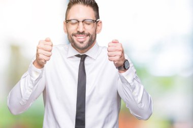 İzole arka kolları olan başarı için heyecan üzerinde gözlük takan genç yakışıklı iş adamı zafer kutluyor gülümseyen kaldırdı. Kazanan kavramı.