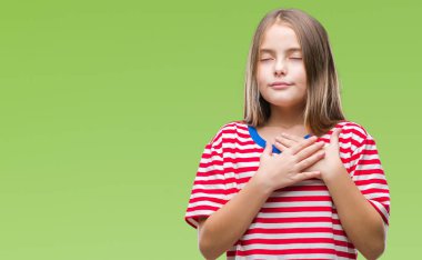 Genç güzel kız ile gülümseyen izole arka plan üzerinde kapalı gözler ve yüzünde minnettar jest ile göğüs üzerinde eller. Sağlık kavramı.