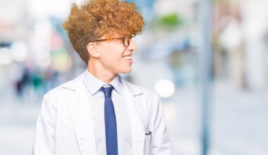 Uzak tarafına yüzünde, doğal ifade gülümseme ile seyir gözlüklü genç yakışıklı bilim adam. Kendine güvenen gülüyor.