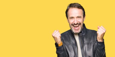 Orta yaş yakışıklı adamın siyah deri ceket kutluyor giydiğini şaşırttı ve başarı için kaldırdı kollarını açarak hayret ve gözleri açık. Kazanan kavramı.