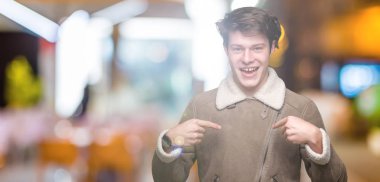 Yüzünde gülümseme ile kendinden emin görünüyorsun, kendini gururlu ve mutlu parmakları ile işaret izole arka plan üzerinde kış ceket giyen genç yakışıklı adam.