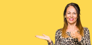 Leopar hayvan baskı elbise gösteren palm el giyen ve yukarıya, mutlu ve neşeli gülümseyen baş parmakları Tamam jest yapıyor güzel orta yaş kadın