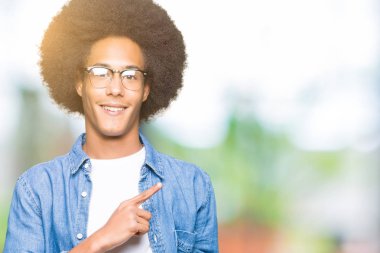 Gülümseyen ve iki elleri ve parmakları ile tarafına işaret kamera bakarak gözlüklü afro saçlı genç Afro-Amerikan adam.
