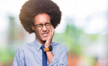 Afro saçlı diş ağrısı veya dişlerde dişlerle ilgili hastalık nedeniyle ağız acı ifadesi ile el ile dokunmak gözlüklü genç Afro-Amerikalı iş adamı. Diş hekimi kavramı.