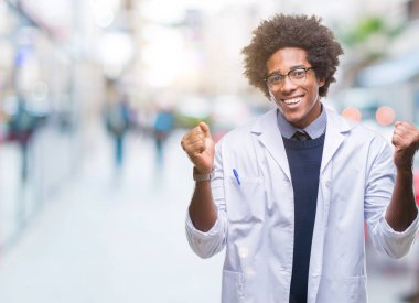 İzole arka plan kutlama üzerinde Afro Amerikalı doktor bilim adamı adam şaşırttı ve başarı için kaldırdı kollarını açarak hayret ve gözleri açık. Kazanan kavramı.