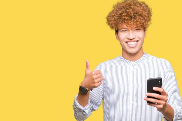 年轻英俊的男人使用智能手机快乐与大大的微笑做确定的迹象 用手指竖起大拇指 优秀的标志 — 图库照片