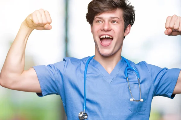 若い医者は 誇りに思って笑顔腕の筋肉を示す孤立した背景に医療制服を着てします フィットネスの概念 — ストック写真