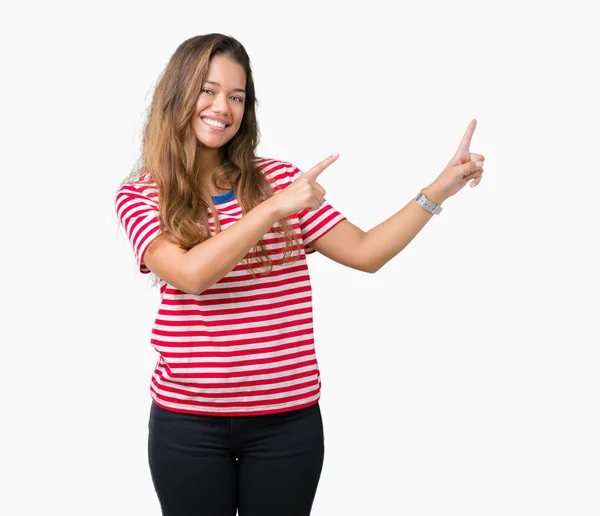 年轻美丽的黑发女人穿着条纹 T恤在孤立的背景微笑 看着相机指向用两只手和手指的一侧 — 图库照片