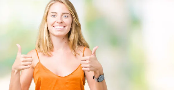 美丽的年轻女子穿着橙色衬衫在孤立的背景成功标志做积极的手势 竖起大拇指微笑和快乐 带着欢快的表情 获胜者的手势看着镜头 — 图库照片