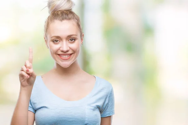 年轻的金发女人在孤立的背景下 指着成功的想法 退出和快乐 第一个 — 图库照片