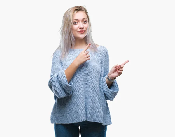 年轻的金发女人穿着冬季毛衣在孤立的背景下微笑着 看着相机指着两只手和手指的侧面 — 图库照片